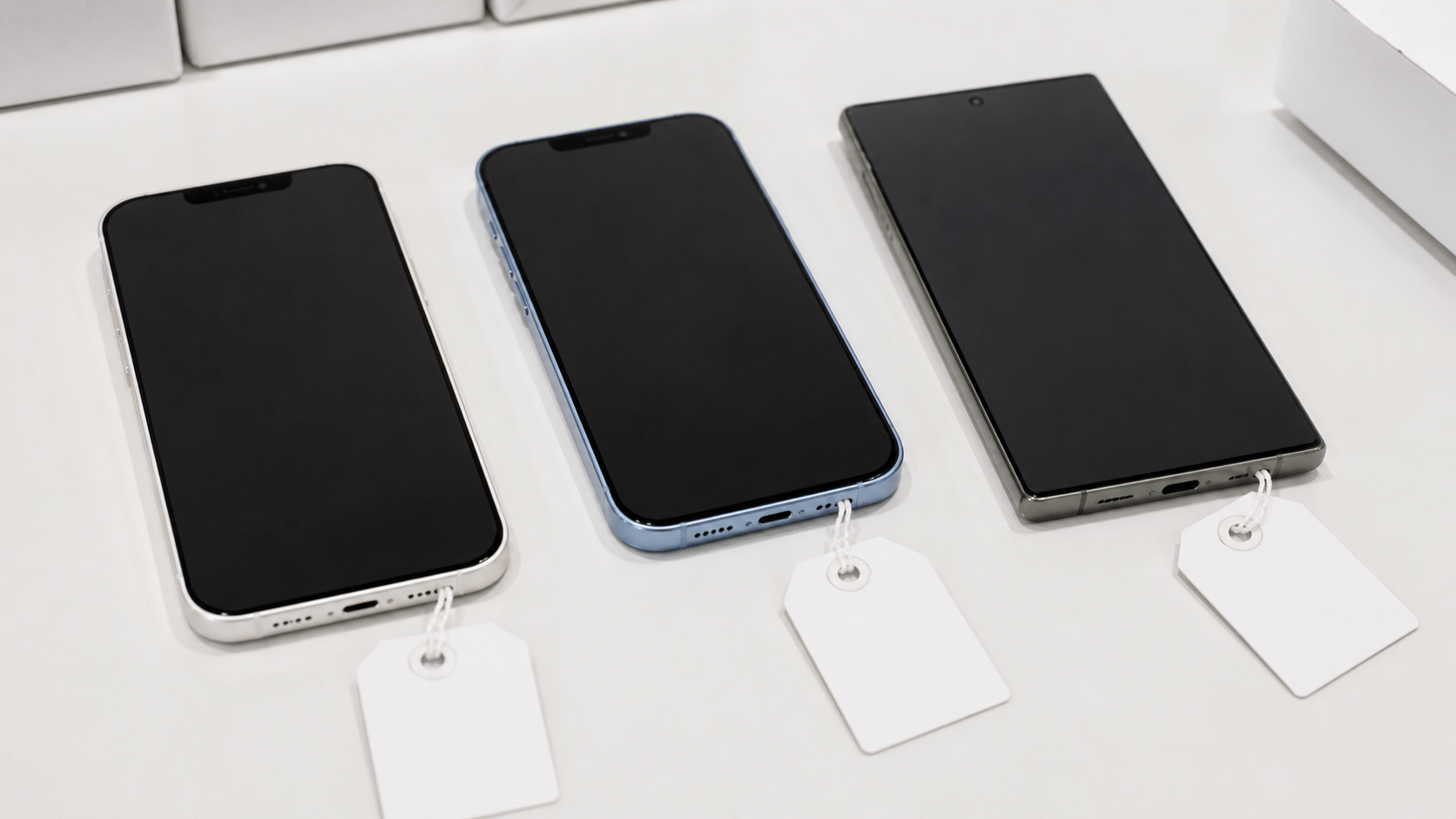 Stari iPhones i Samsung telefoni na gomili sa biljčicom — simbol cirkularne ekonomije i elektronskog otpada